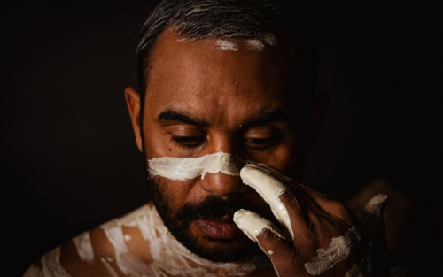 Aboriginal male applying ochre to face - Australian Stock Image