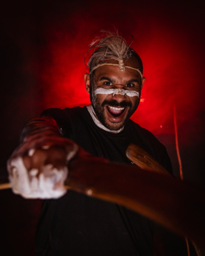 Aboriginal male holding boomerang yelling creative studio portrait - Australian Stock Image