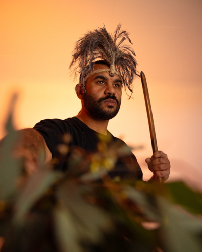 Aboriginal man looking away holding gum leaves towards foreground - Australian Stock Image