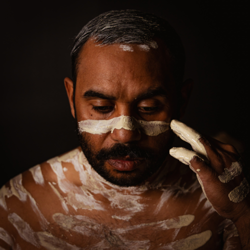 Aboriginal man painting his body with an ochre - Australian Stock Image