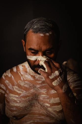 Aboriginal man painting his face with an ochre - Australian Stock Image
