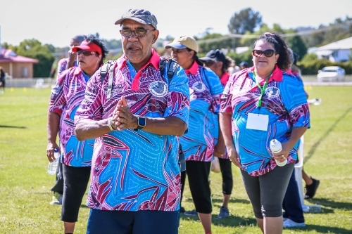 Aboriginal man wearing hat and glasses rubbing hands together - Australian Stock Image