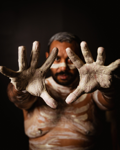 Aboriginal man with body paint extending his palms in front - Australian Stock Image