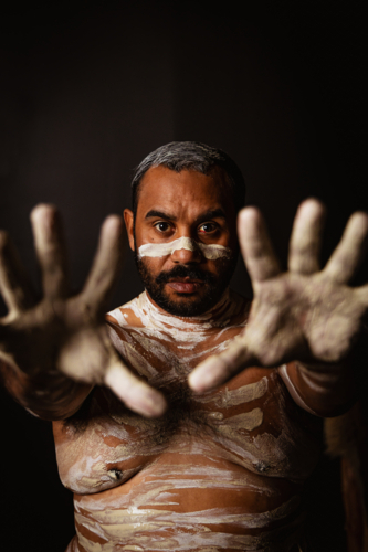 Aboriginal man with body paint extending his palms in front - Australian Stock Image