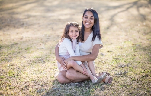 Aboriginal mother sitting with mixed race daughter on lap
