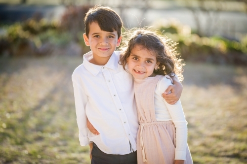 Aboriginal twin brother and sister standing with arms around each other - Australian Stock Image