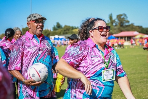 Aboriginal woman wearing glasses standing with a man holding ball - Australian Stock Image