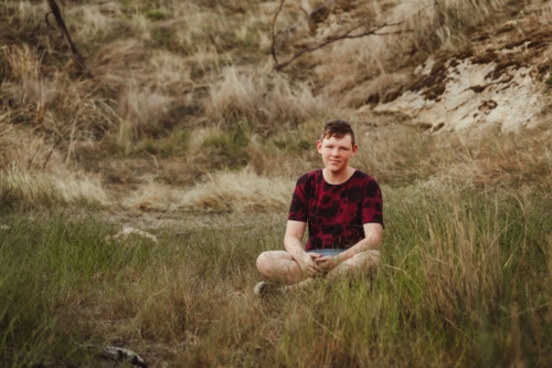 Adolescent boy sitting in grass in the Australian bush - Australian Stock Image