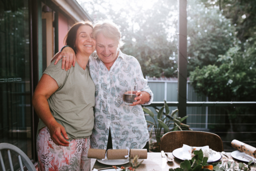 Adult mother and daughter hugging each other on the porch - Australian Stock Image