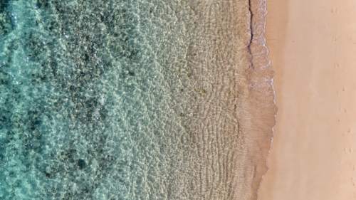 Aerial of a beach with crystal clear water and yellow sand - Australian Stock Image