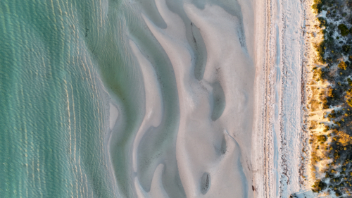 Aerial of the tide coming in at a beach at golden hour - Australian Stock Image