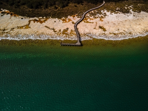 aerial shot of a beach walkway with bushes, trees and waves on a sunny day - Australian Stock Image