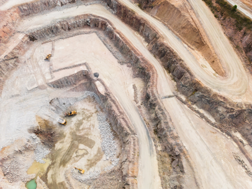 Aerial view looking down into a quarry pit with machinery on the ground - Australian Stock Image