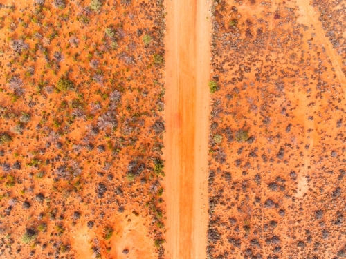 Aerial view looking down on dirt road through outback scrub - Australian Stock Image