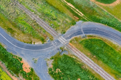 Aerial view of a country road winding through a railway crossing - Australian Stock Image