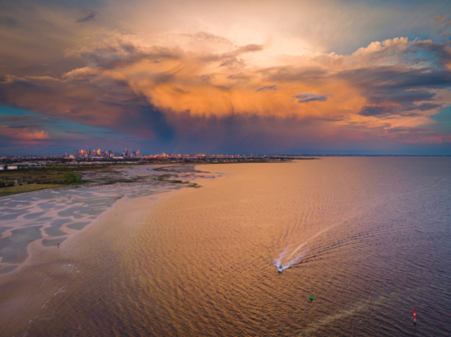 Aerial view of a dramatic storm cloud a over small boat and city skyline - Australian Stock Image