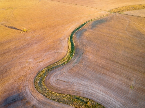 Aerial view of a green creek bed winding through a ploughed paddock at Dimboola in Victoria