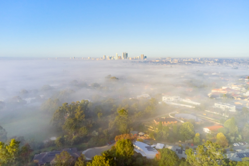 Aerial view of a Perth foggy landscape in the early morning, with the city skyline on the horizon - Australian Stock Image