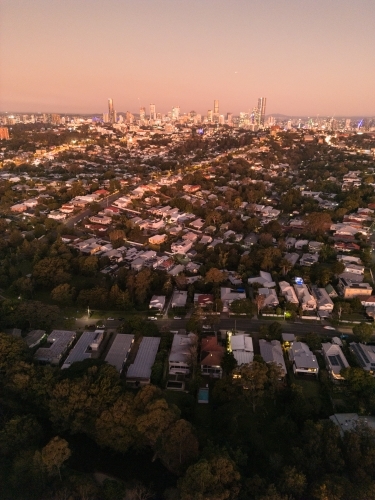 Aerial view of a residential area under the sunset sky with city skyline at the edge - Australian Stock Image