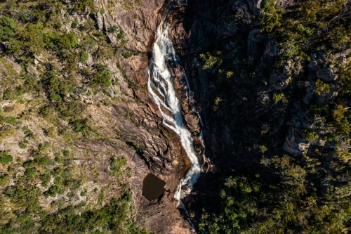 Aerial view of a waterfall flowing down a rocky cliff. - Australian Stock Image