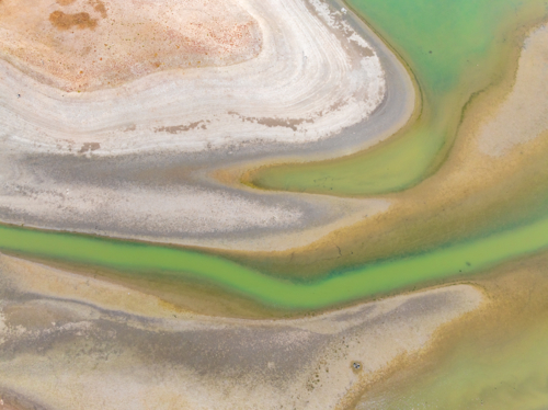 Aerial view of abstract patterns in streams of water in the drying bed of a reservoir - Australian Stock Image