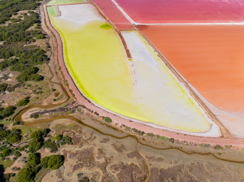 Aerial view of colourful salt evaporation ponds and levee banks at a coastal salt farm - Australian Stock Image