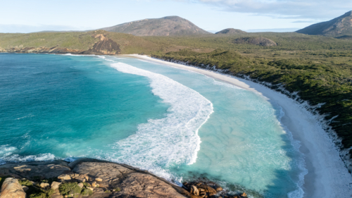 Aerial view of crescent-shaped beach with turquoise water. - Australian Stock Image