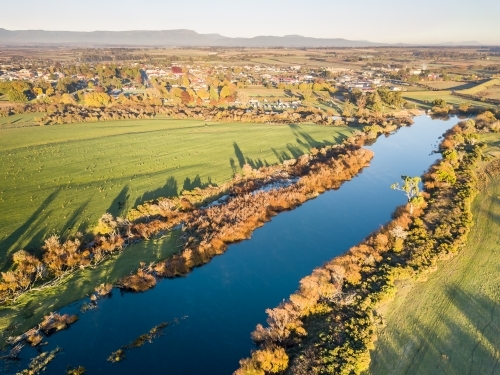 Aerial view of golden trees lining the banks of a river in Autumn - Australian Stock Image