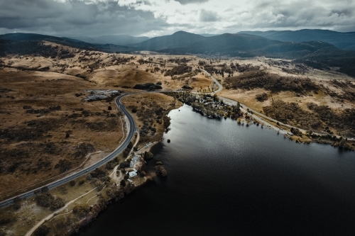 Aerial view of outskirts of Jindabyne with the 'Alpine Way' leading into the Snowy Mountains - Australian Stock Image