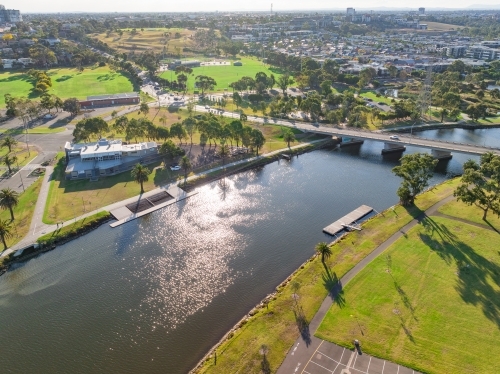 Aerial view of parkland on the banks of a city river with a road bridge over it - Australian Stock Image