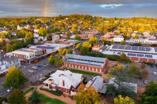 Aerial view of rainbow and cloud formations over a regional town's historic streetscape - Australian Stock Image
