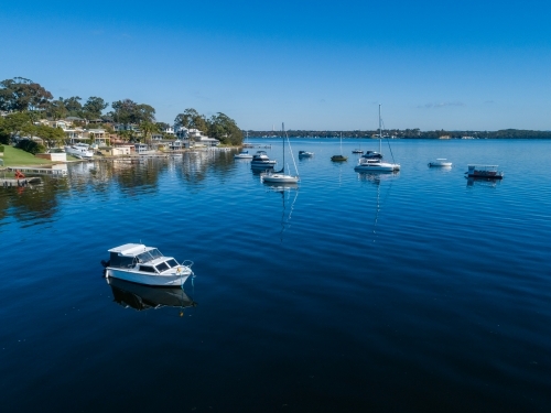 Aerial view of recreational boats in water of Lake Macquarie beside waterfront housing - Australian Stock Image