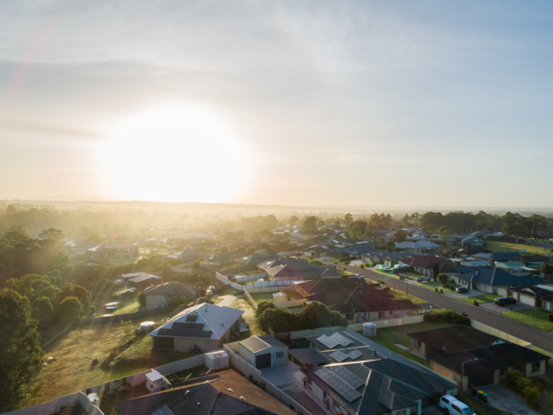 Aerial view of sunrise over suburbs with dew on grass - Australian Stock Image