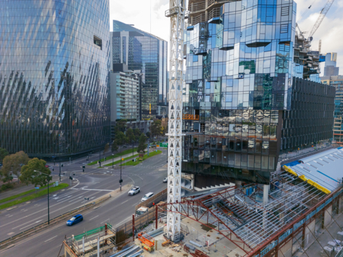 Aerial view of tall crane on a construction site in front of a city skyline - Australian Stock Image