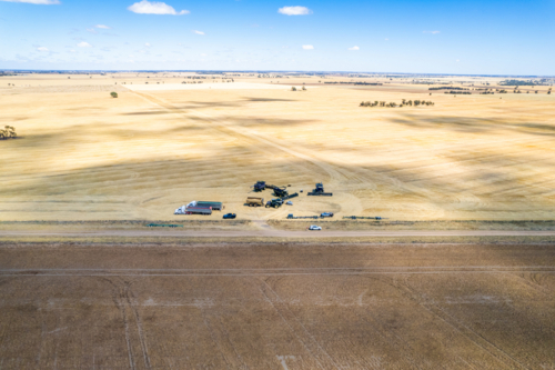 Aerial view of transport trucks and combine harvester on the field. - Australian Stock Image