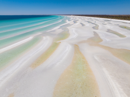 Aerial view of turquoise water along a pristine white sandy beach - Australian Stock Image