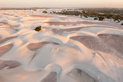 Aerial view of white sand dunes stretching to the horizon in late afternoon sunshine - Australian Stock Image