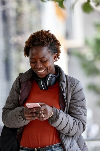 African woman having fun in city checking device - Australian Stock Image