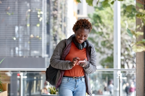 African woman having fun in city checking mobile phone - Australian Stock Image