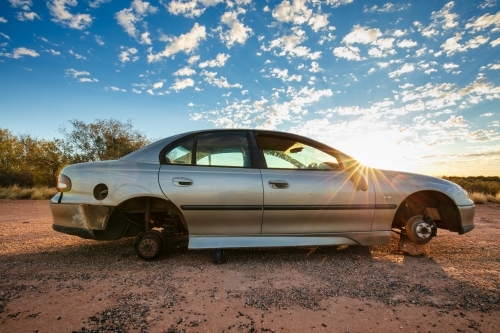 An abandoned sedan without wheels sits besides the Stuart Highway in Central Australia - Australian Stock Image