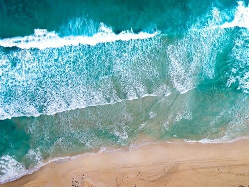 An aerial view of waves rolling to the shoreline - Australian Stock Image