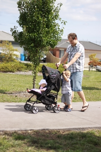 An Australian father pushing a baby in a pram with his toddler son on a warm sunny day - Australian Stock Image