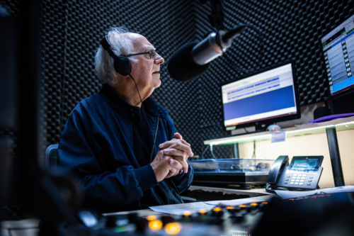 An elderly caucasian man DJs and presents his music show on live radio in Melbourne, Australia - Australian Stock Image