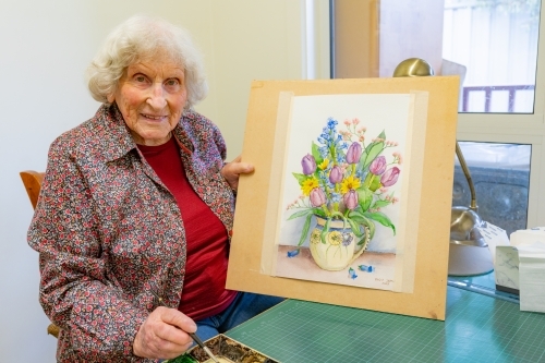 An elderly lady artist display her finished water colour painting - Australian Stock Image