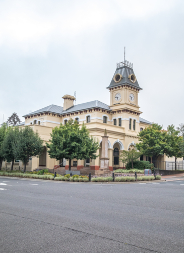 An old Post Office building in a country town bordered with green trees - Australian Stock Image