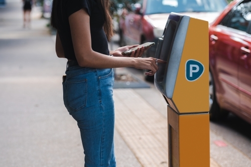 anonymous woman using car parking machine - Australian Stock Image