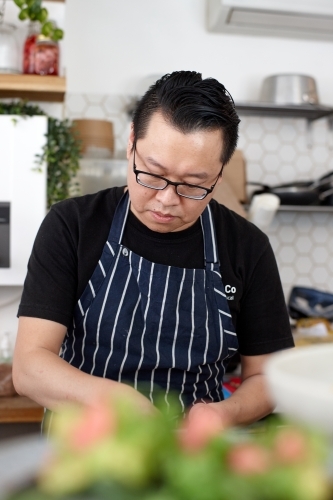 Asian chef working in kitchen at organic food cafe - Australian Stock Image