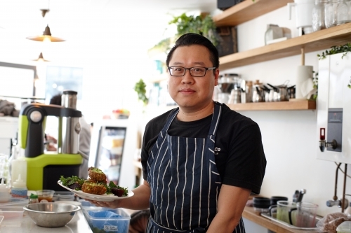 Asian chef working in kitchen at organic food cafe - Australian Stock Image