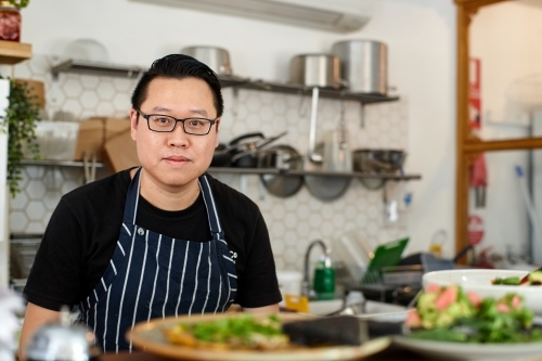 Asian chef working in kitchen at organic food cafe - Australian Stock Image