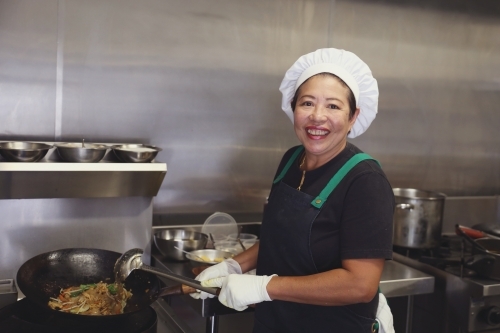 Asian female chef in commercial kitchen - Australian Stock Image